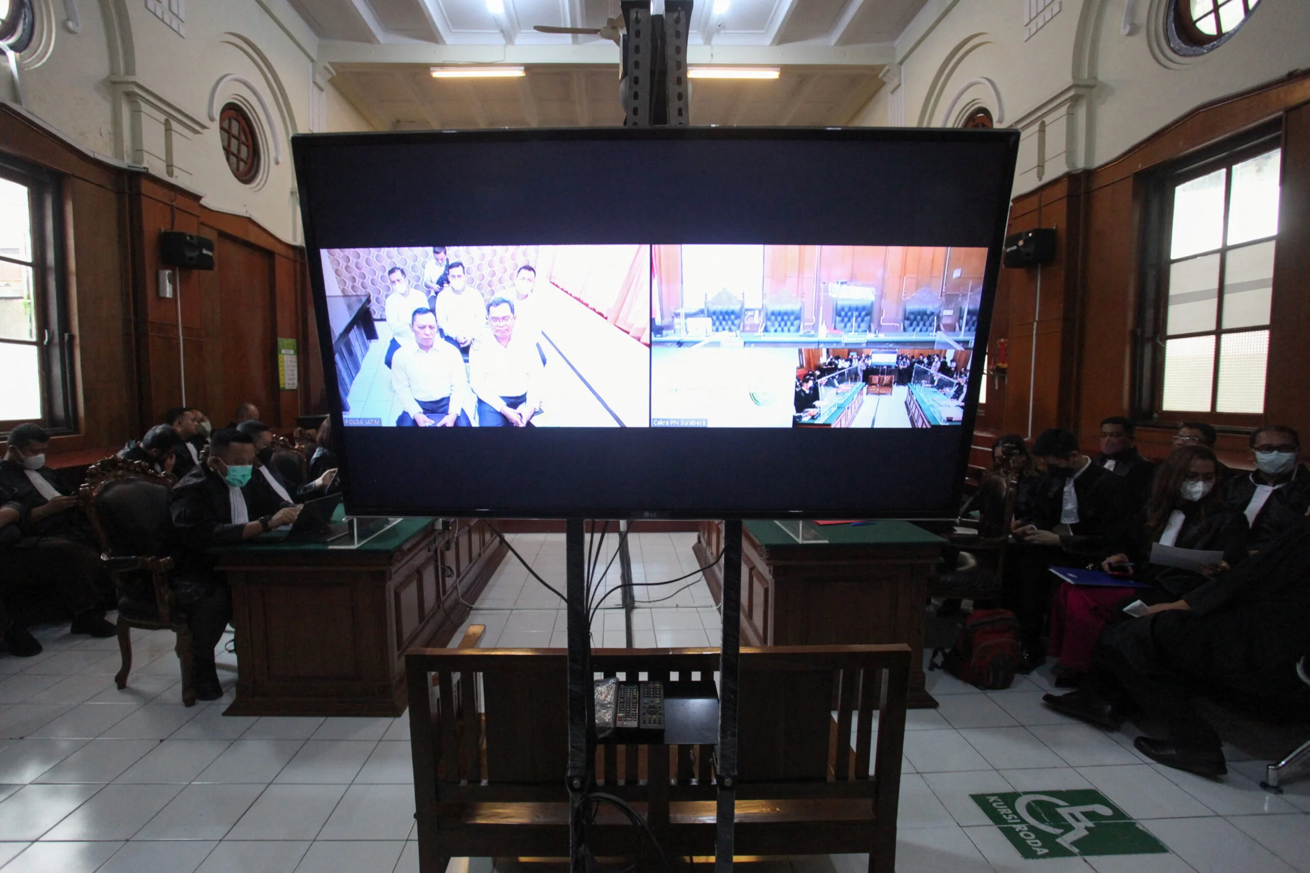 מסך המראה את הנאשמים במהלך משפט על רמיסה המונית במהלך משחק כדורגל במזרח ג'אווה, 2022. צילום: רויטרס